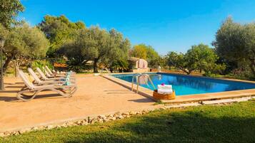 A swimming pool with lounge chairs and a stone structure in a landscaped garden.