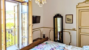 Un dormitorio con cama, candelabro, espejo, televisor y puerta.