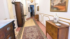 Un pasillo con piso de mármol, un tapete estampado, un aparador de madera, un jarrón y un cuadro enmarcado en la pared.