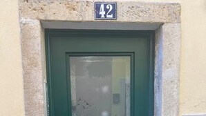 A green door with a number 42 sign above it, set in a stone frame.