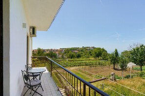 A balcony with a table and chairs, a railing, and a view of a vineyard and houses in the distance. - Apartment 'Vista Mare A Due Passi Dal Sentiero Degli Dei' with Sea View, Wi-Fi and Air Conditioning (Agerola)