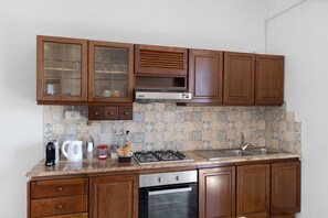 Una cocina con armarios de madera, estufa a gas, lavaplatos y lavadero.
