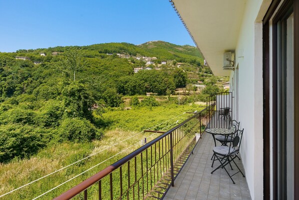 Un balcon donnant sur un village perchĂ© sur une colline, avec une balustrade et du mobilier dâextĂ©rieur.