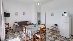 A compact living space with a dining table, a sofa, a small TV, and a refrigerator. - Apartment 'Familiare A Due Passi Dal Sentiero Degli Dei' with Sea View, Wi-Fi and Air Conditioning (Agerola)