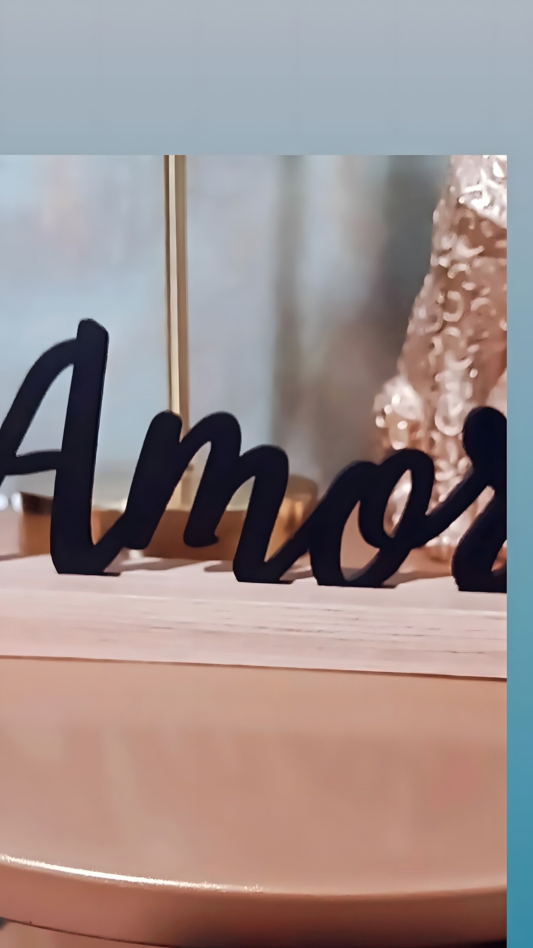 Primer plano de un adorno negro que deletrea 'Amor' sobre una superficie clara.