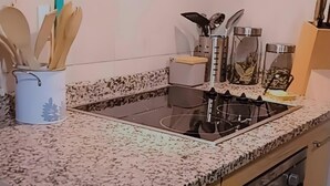 A kitchen with a granite countertop, stainless steel appliances, wooden utensils, and a ceiling fan.