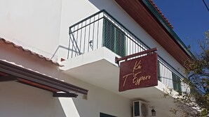 A building with a balcony, a sign reading 'La Taverna,' and a door with a green shutter.