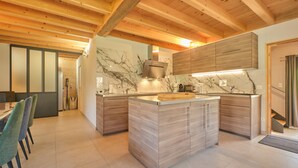 Een moderne keuken met houten balken, marmeren aanrechtbladen en inbouwmeubels.