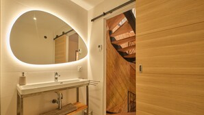 Een moderne badkamer met een grote spiegel, een wastafel en een houten wastafelmeubel.