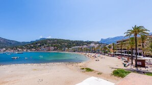 Une plage avec des bateaux, un rivage sablonneux et des bâtiments en arrière-plan.