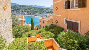 Un bâtiment de style méditerranéen, doté d’une façade en pierre, d’un balcon offrant une vue sur la mer et d’un jardin luxuriant.