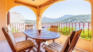 Un balcon avec une table ronde et quatre chaises, offrant une vue panoramique sur une ville et des montagnes.