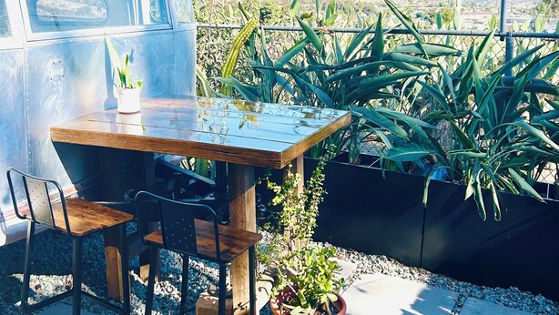 Un comedor con una mesa y sillas, una planta en maceta y vistas a las montañas.