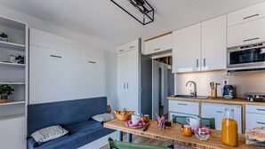 A compact kitchen with a microwave, coffee maker, and a dining area with a table, chairs, and a sofa.