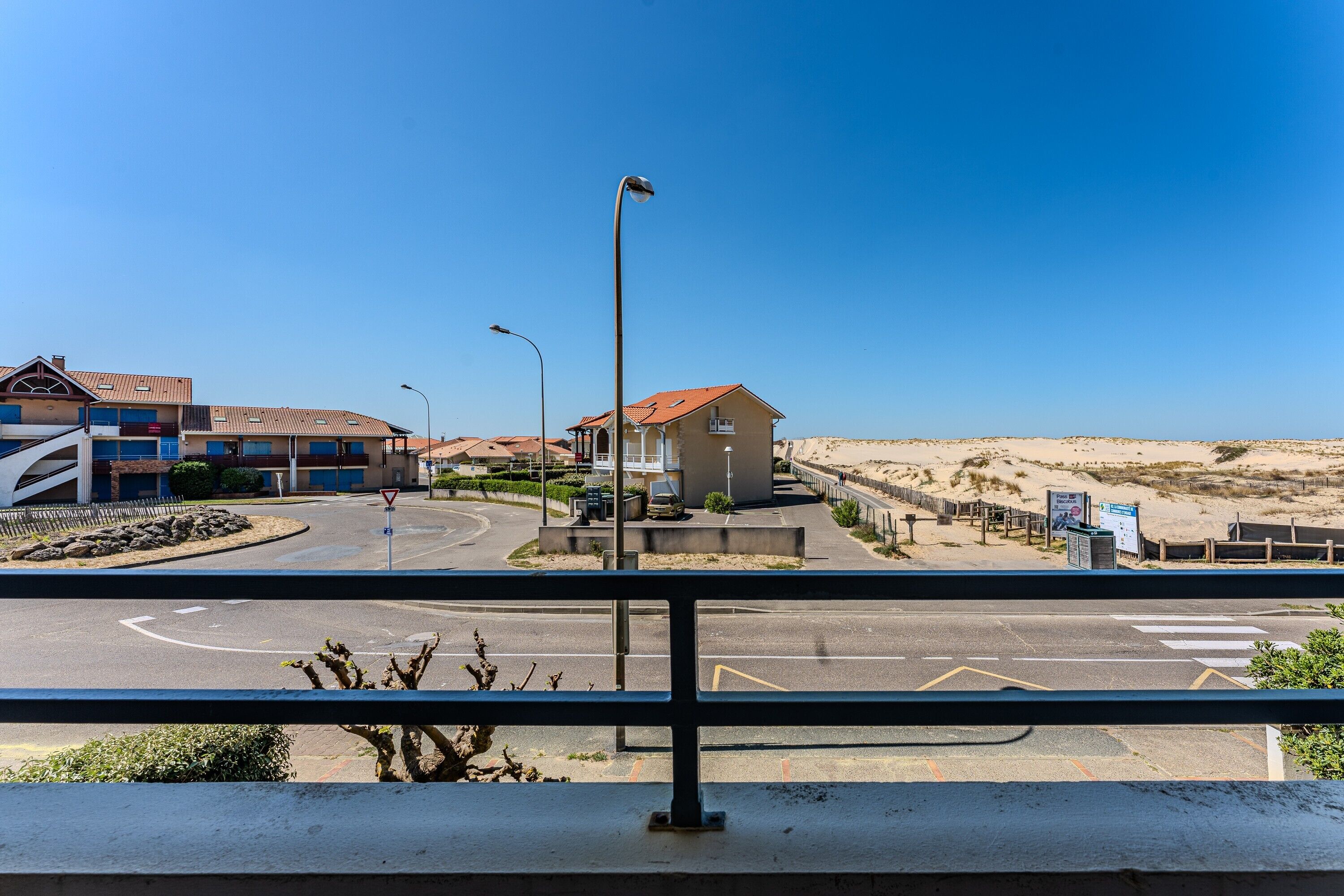A road intersection with a pedestrian crossing, a small building, and a clear blue sky.