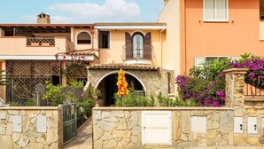 A Mediterranean-style building with a stone facade, a balcony with a wrought iron railing, and a small entrance with a stone archway. - Cozy Holiday Home "Casa Oleandro" in Villasimius – Relaxation & Comfort Near the Sea (Villasimius)