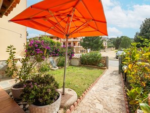 Un sendero pavimentado que conduce a un edificio con un muro de piedra y plantas en macetas.