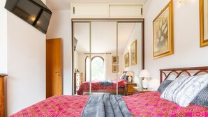 A bedroom with a bed, a mirror, a wardrobe, and a door leading to another room. - Cozy Holiday Home "Casa Oleandro" in Villasimius – Relaxation & Comfort Near the Sea (Villasimius)