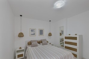 Ein Schlafzimmer mit Bett, Nachttischen, einer Kommode und Wandleuchten.