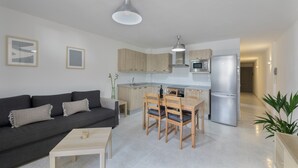 A modern apartment with a living room, dining area, kitchen, and a hallway.
