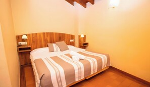 A neatly made bed with striped bedding, two bedside lamps, and a wooden headboard.