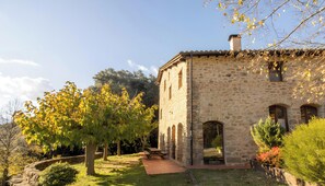 A stone building with a patio, trees, and a clear sky.