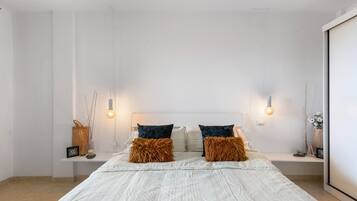 A modern bedroom with a large bed, two bedside tables, and a nightstand.