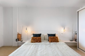 Una camera da letto moderna con un letto grande, due comodini e un tavolino da notte.