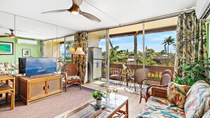 A spacious living area with a television, sofa, and dining table.