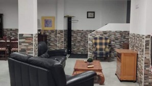 A spacious lobby with a black leather sofa, a wooden coffee table, and a checkered armchair. There is a stone-patterned wall and a framed picture on the wall. - Loft Los Olivos in Algar (Algar)