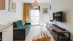 Una sala de estar moderna con un sofá verde, una mesa de centro de madera y un televisor de pantalla plana montado en la pared.