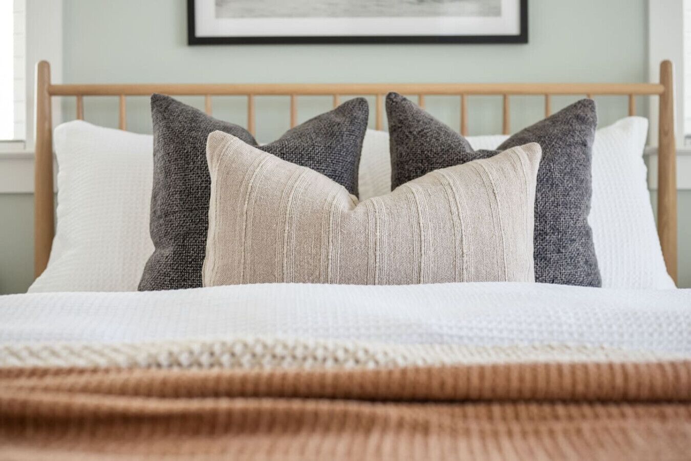 A bed with a wooden headboard, white and gray pillows, and a brown blanket.