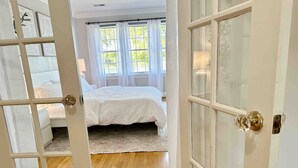 Ein Schlafzimmer mit einem Bett, einem Fenster mit Vorhängen und Holzboden.