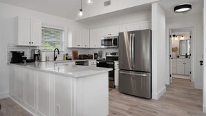 A modern kitchen with white cabinetry, stainless steel appliances, and a central island. - Serenity House-Water Views, Pet Friendly & Hot Tub (Kill Devil Hills)