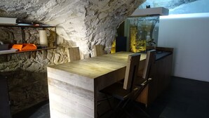 A kitchen with a rustic stone wall, wooden table, and bar stools.