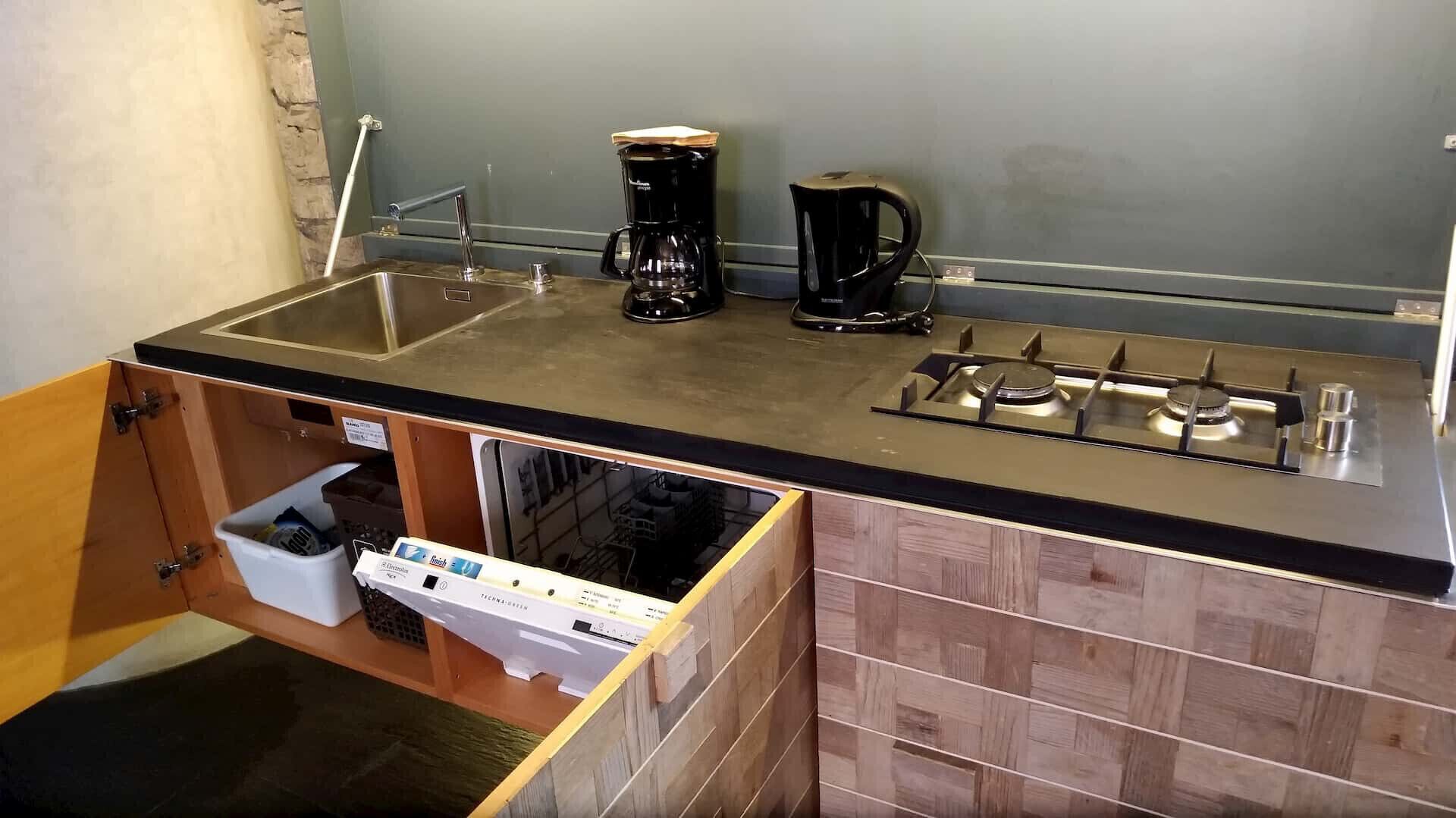 A compact kitchen with a gas stove, a coffee maker, and a sink.