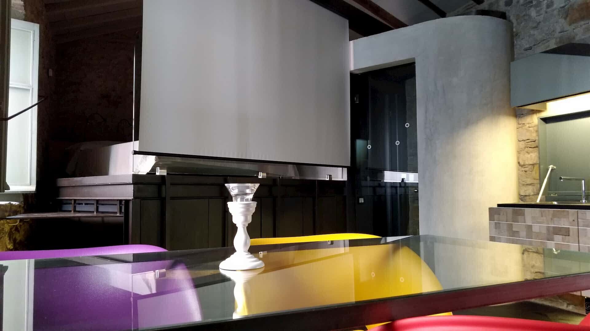 Eine moderne Küche mit einer Glasarbeitsplatte, einer weißen Vase und einer gelben Wand.