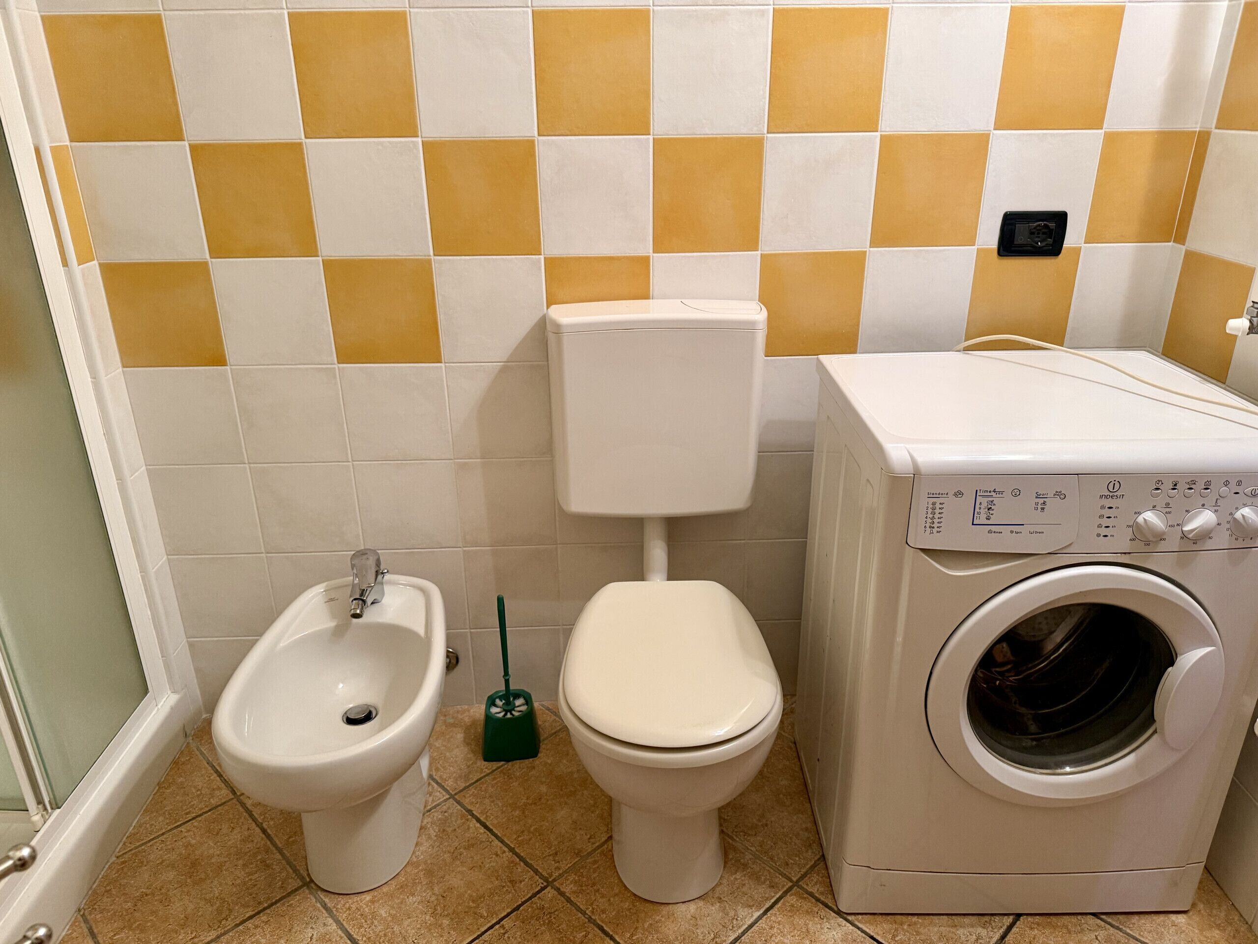 Un baño con bidé, inodoro y lavadora.
