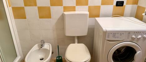 Un baño con bidé, inodoro y lavadora.