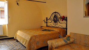A bedroom with a bed, a sofa, and a wall-mounted light fixture.
