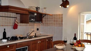 A kitchen with wooden cabinets, a gas stove, a sink, and a window with a view.
