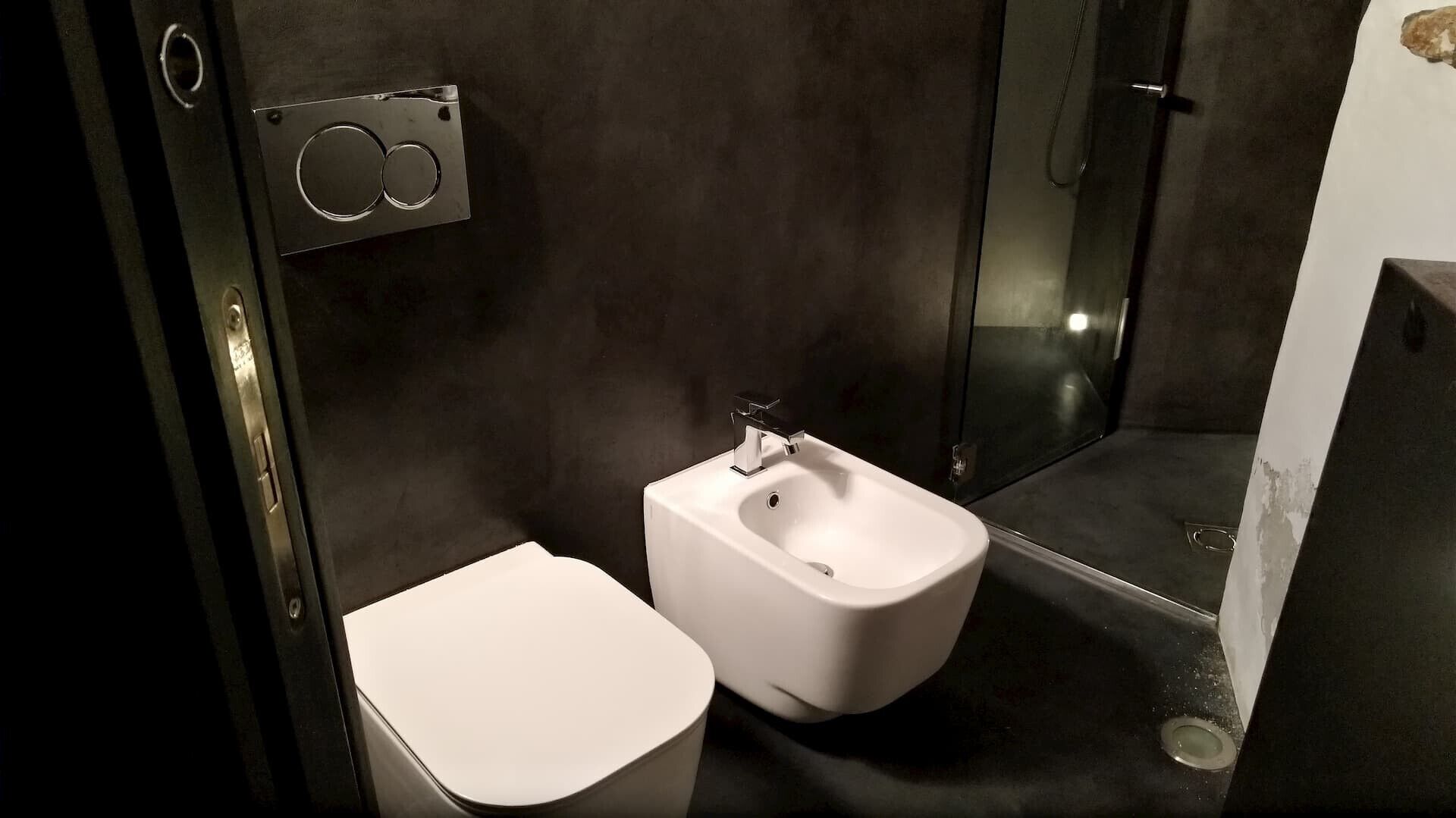 A modern bathroom with a bidet, a toilet, and a glass shower enclosure.