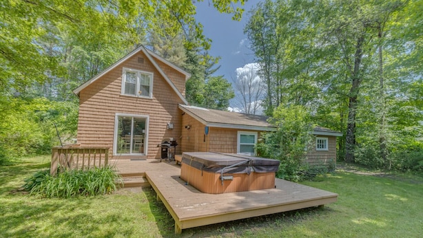 A two-story log cabin with a hot tub in the backyard.
