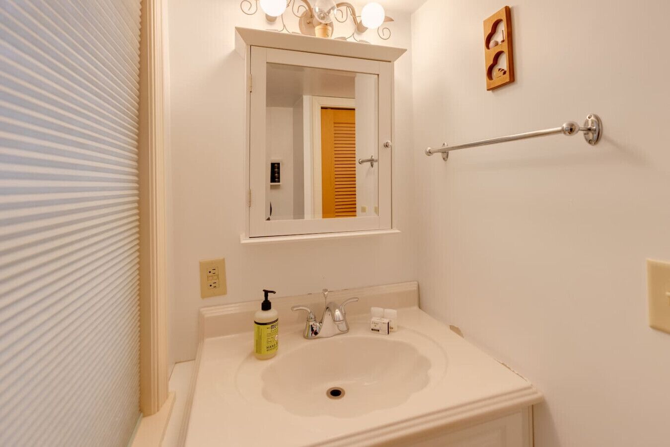 Un baño con un lavabo blanco, un espejo y un toallero.