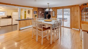 A cozy kitchen with wooden flooring, a dining table with chairs, a built-in oven, and a large window offering a view of the outside.