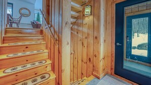 Eine Holztreppe führt zu einem Raum mit einer Glastür, einer Holzwand und einem Bilderrahmen mit einem Reh.