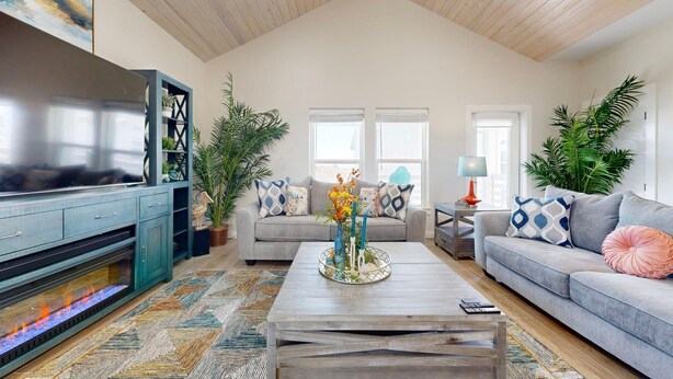 A living room with a TV, sofa, coffee table, and plants. - PPLM401 Private Heated Pool, Golf Cart Included, Close to the Beach (Port Aransas)