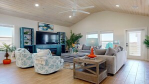 A spacious living room with a television, a sofa, two armchairs, a coffee table, and a ceiling fan. - PPLM401 Private Heated Pool, Golf Cart Included, Close to the Beach (Port Aransas)