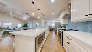 A modern kitchen with white cabinetry, a large island, and pendant lighting. - PPLM401 Private Heated Pool, Golf Cart Included, Close to the Beach (Port Aransas)