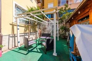 An outdoor patio with a pergola, two wicker chairs, and a table. - Guesthouse 'hapa të Lehtë' - Room 1 - Pro Bono (Shkodër)